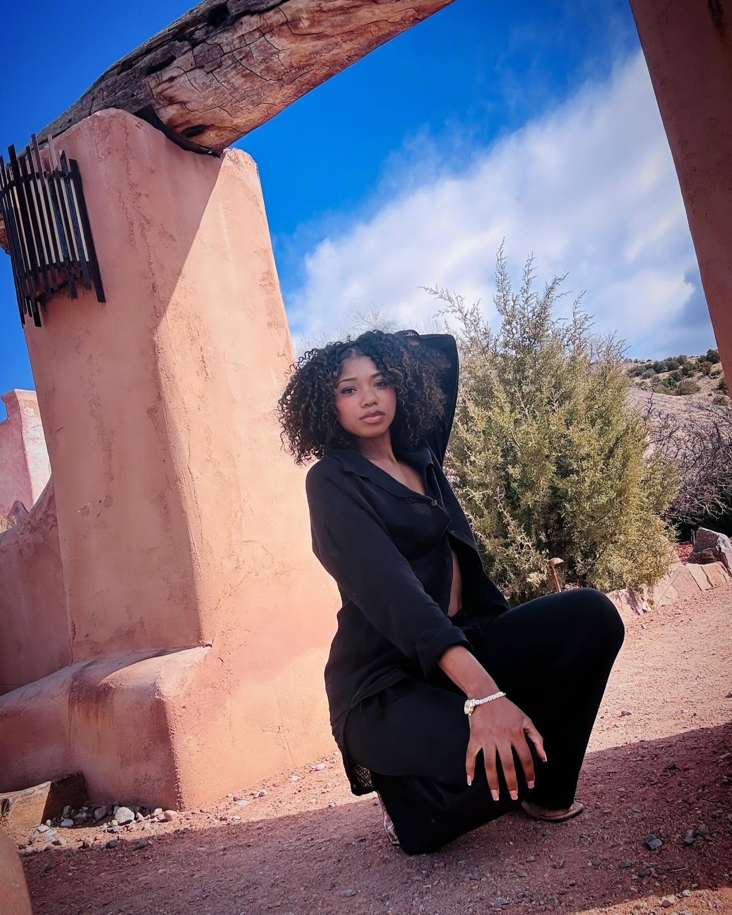 Keyonna in a black outfit beside warm adobe architecture